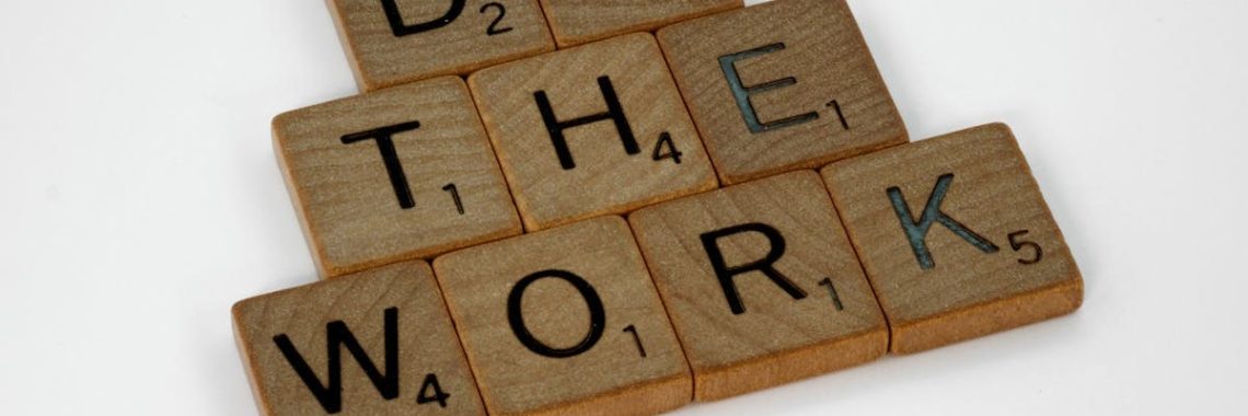 Creative arrangement of Scrabble tiles spelling 'Do the Work' on a white background.